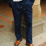 Close-up of a person wearing navy blue corduroy drawstring pants with a matching jacket, paired with a white and navy striped shirt and brown loafers.