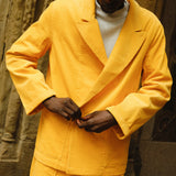 Man wearing full yellow corduroy 'Easy Going Suit'. He is looking down and buttoning up the jacket. 