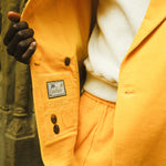 Zoomed-in shot of man holding open the yellow corduroy jacket, to get a glimpse of the interior care label.