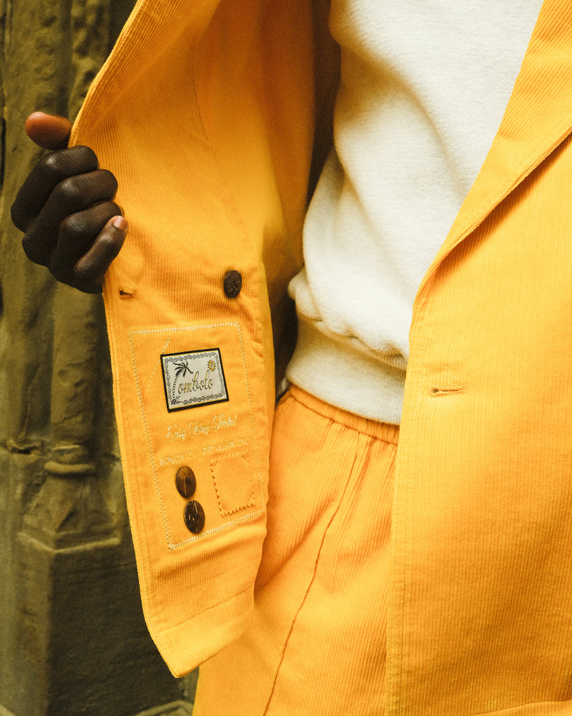Zoomed-in shot of man holding open the yellow corduroy jacket, to get a glimpse of the interior care label.