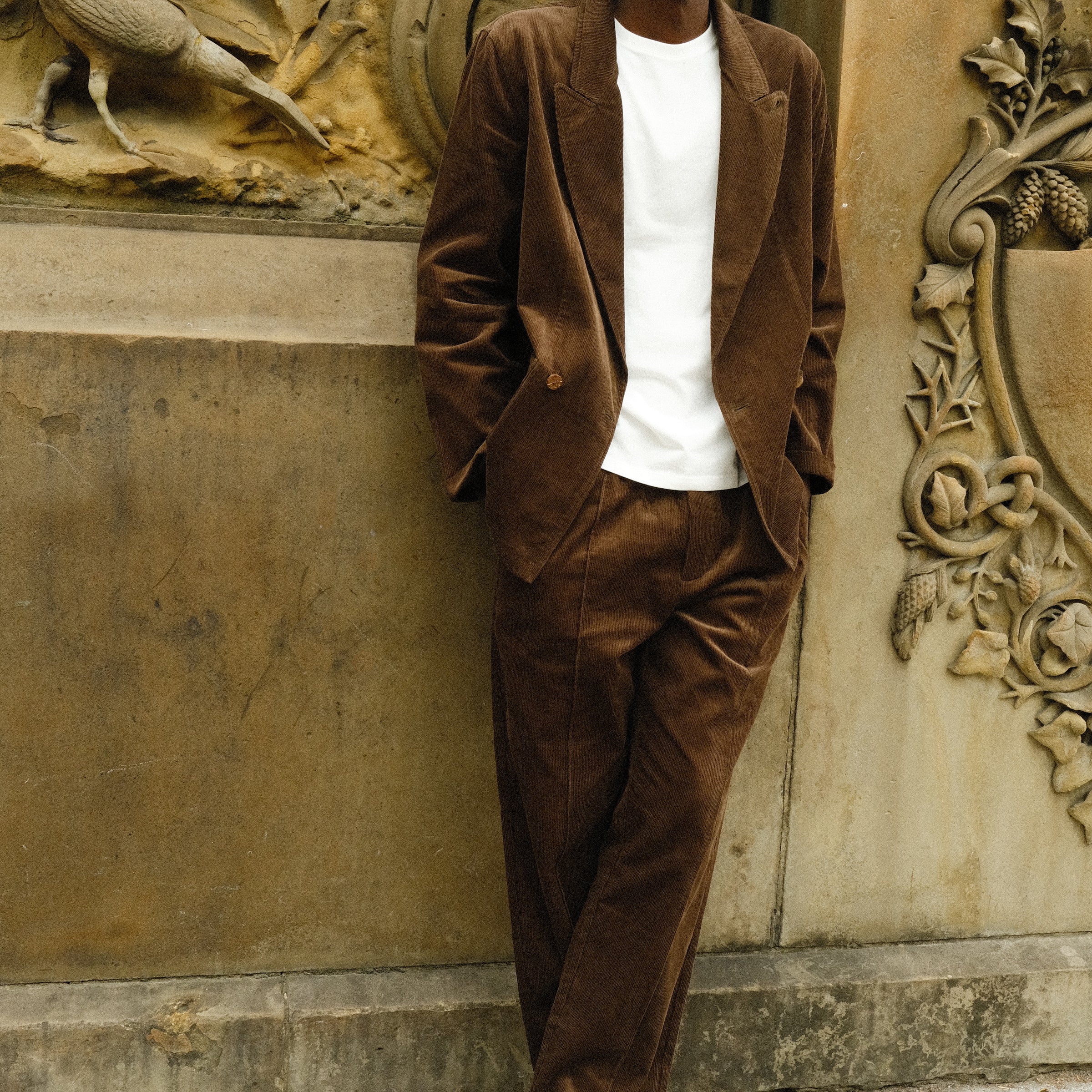 Man wearing a brown corduroy jacket and matching pants, paired with a white shirt and brown loafers.