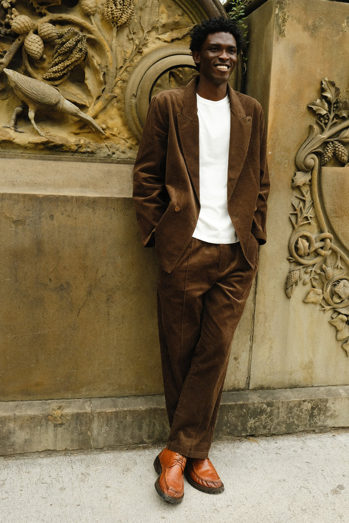 Man wearing a brown corduroy jacket and matching pants, paired with a white shirt and brown loafers.