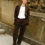 Woman wearing a brown corduroy jacket and matching drawstring pants, paired with a white ringer T-shirt and black loafers.