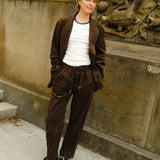 Woman wearing a brown corduroy jacket and matching drawstring pants, paired with a white ringer T-shirt and black loafers.