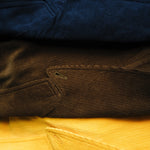 Saffron, brown, and navy corduroy jackets are seen folded on top of each other. 