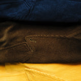 Saffron, brown, and navy corduroy jackets are seen folded on top of each other. 