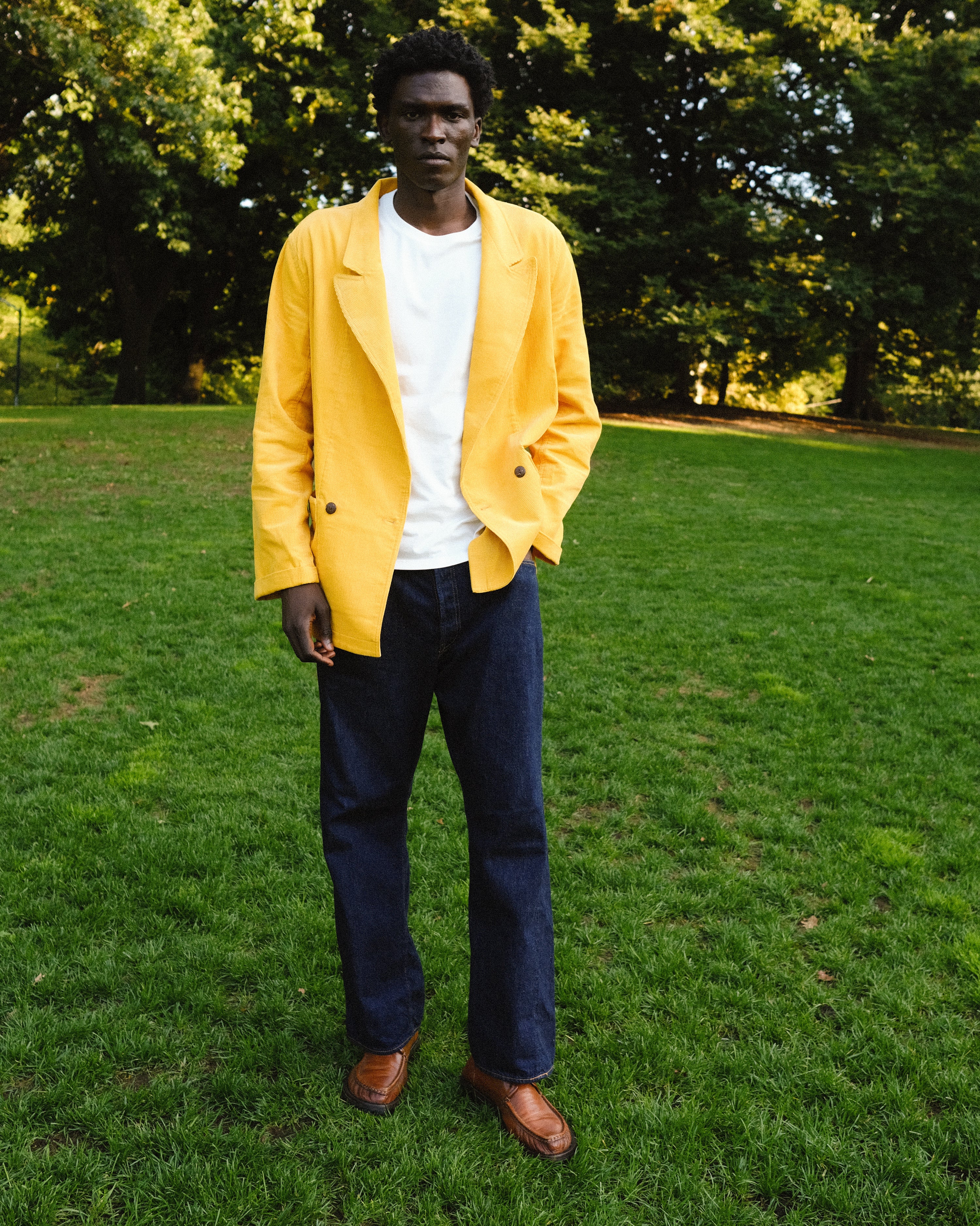 Man wearing the Easy Going Saffron Corduroy jacket with a pair of jeans, seen standing in the grass.