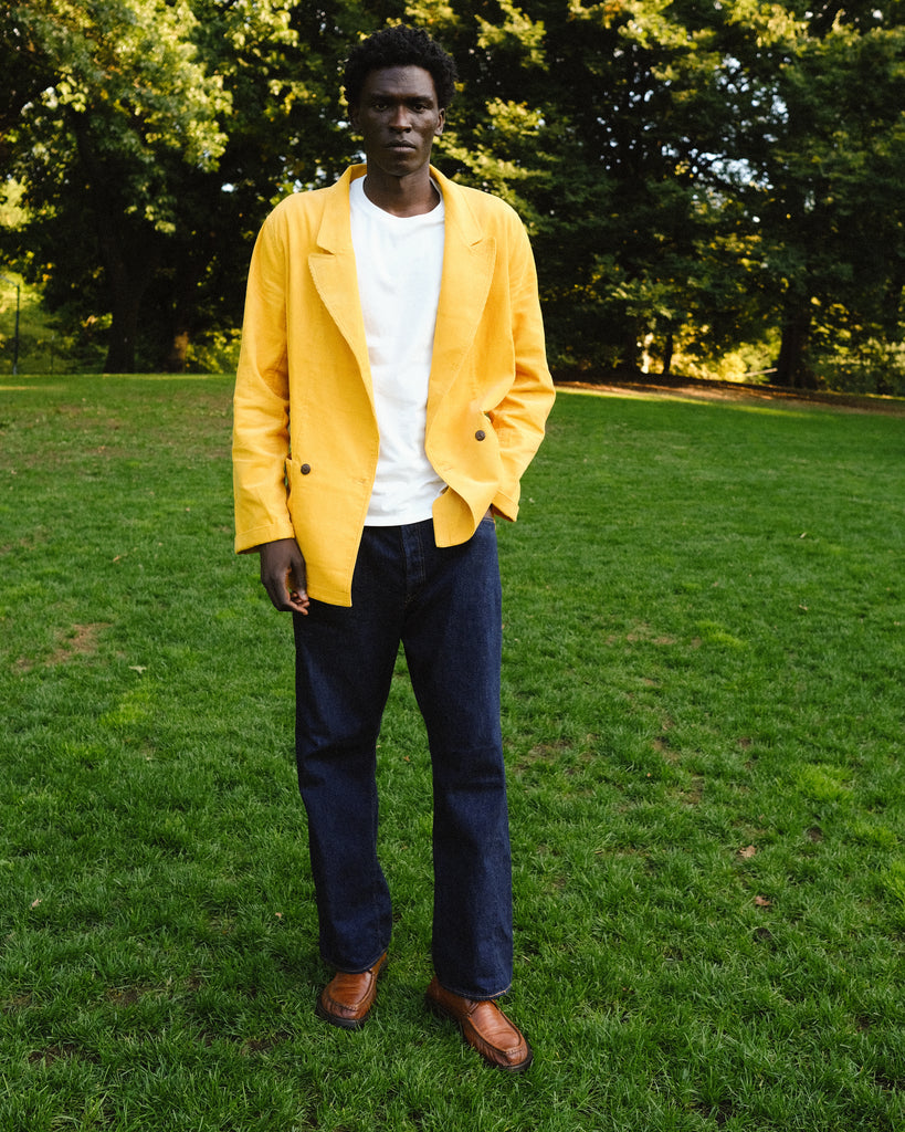 Man wearing the Easy Going Saffron Corduroy jacket with a pair of jeans, seen standing in the grass.