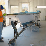Person working on a boat inside a garage.