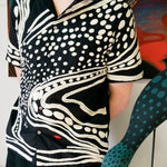 Artist Julian MacMillan wearing black short sleeve cabana shirt with cream chain-stitch embroidery in a loon-inspired dotted and wave pattern, button front.