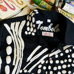 Close-up of black cabana shirt with cream chain-stitch embroidery in a loon-inspired dotted pattern, showing collar and buttons.