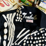 Close-up of black cabana shirt with cream chain-stitch embroidery in a loon-inspired dotted pattern, showing collar and buttons.