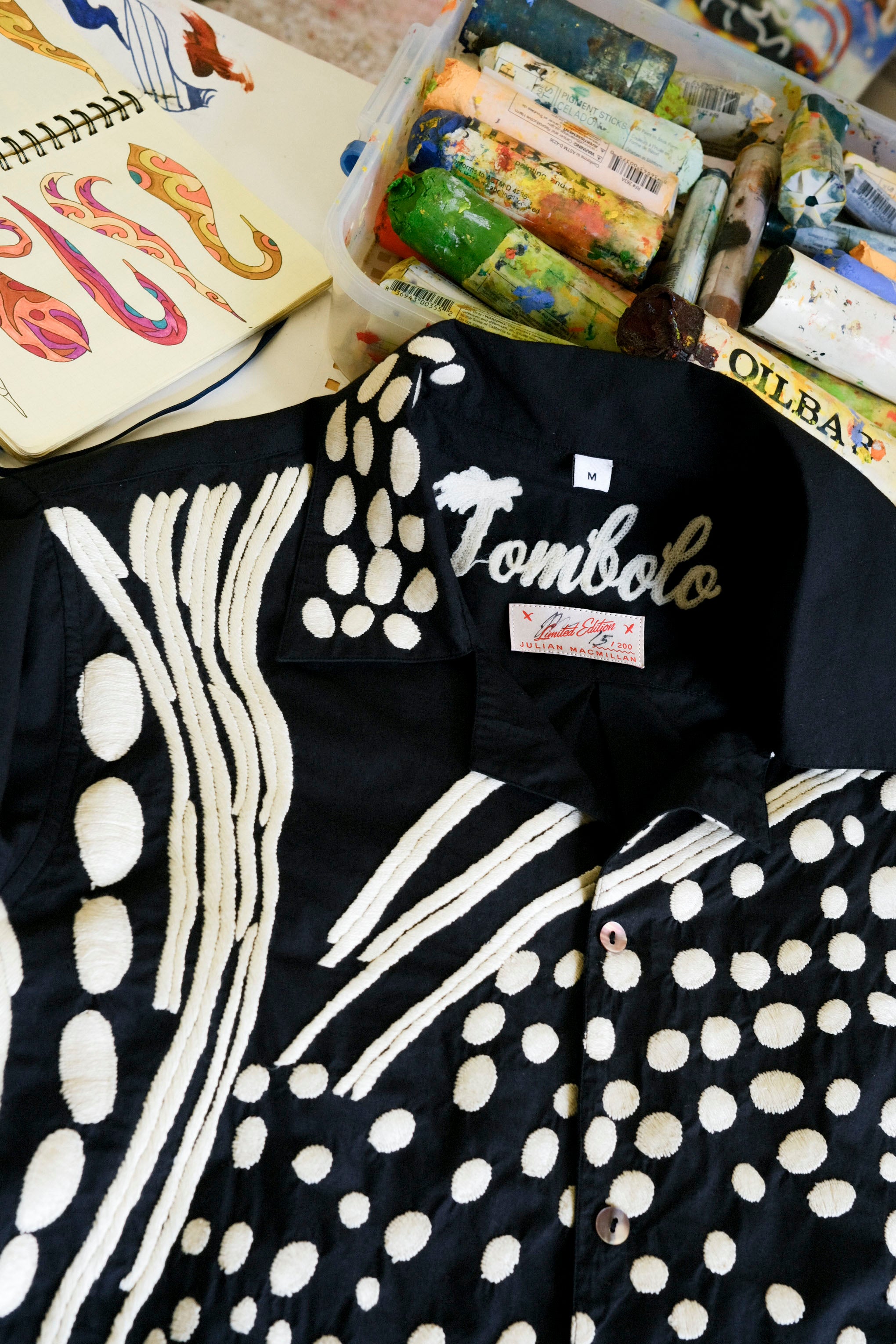 Close-up of black cabana shirt with cream chain-stitch embroidery in a loon-inspired dotted pattern, showing collar and buttons.