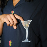 A detailed look at the mesh martini pocket appliqué on the 'Extra Dirty' shirt. The model’s fingertip subtly reveals the sheer quality of the mesh