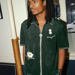 Model looking left, wearing a green terrycloth shirt with playing card and dice embroidery by Tombolo