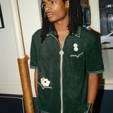 Model looking left, wearing a green terrycloth shirt with playing card and dice embroidery by Tombolo