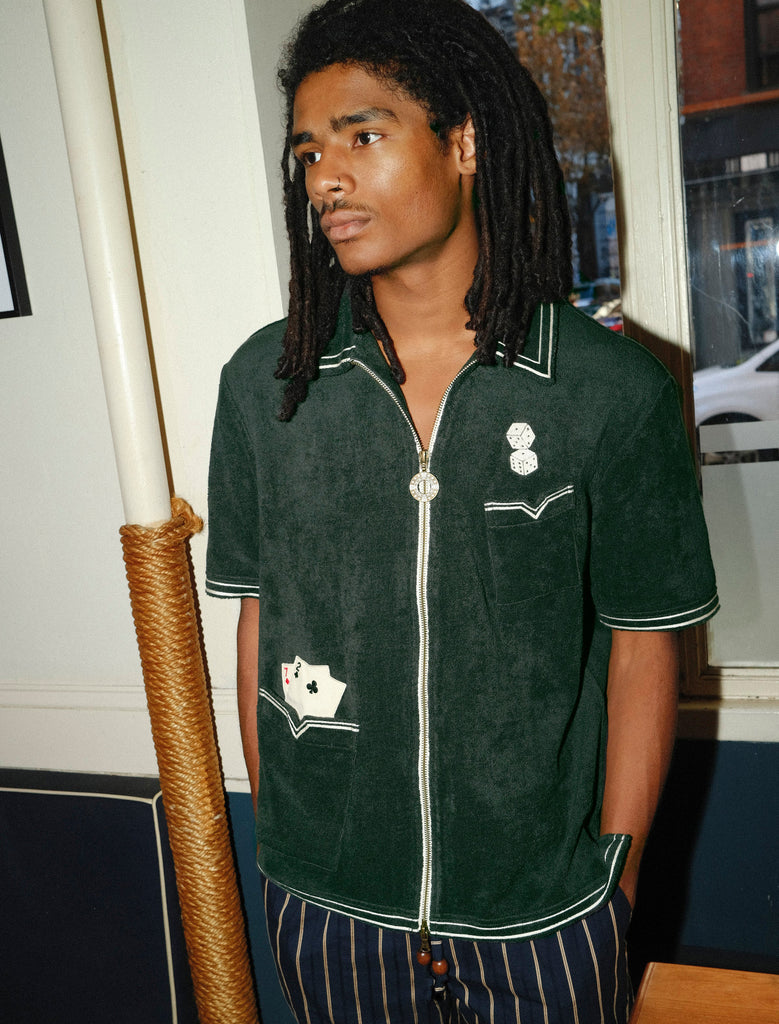 Model looking left, wearing a green terrycloth shirt with playing card and dice embroidery by Tombolo