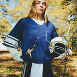 Woman wearing blue mesh jersey, and carrying a football helmet in her arm. 