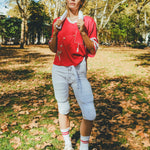 Woman wearing a red mesh football jersey and standing in a park.