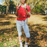 Woman wearing a red mesh football jersey and standing in a park.