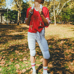 Woman wearing a red mesh football jersey and standing in a park, wearing a towel around her neck.