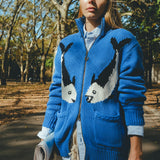 Female model wearing a blue cardigan with fish patterns in a park setting.