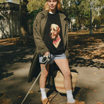 Woman wearing a black knit sweater with an intarsia dog portrait on the front and a red collar detail.