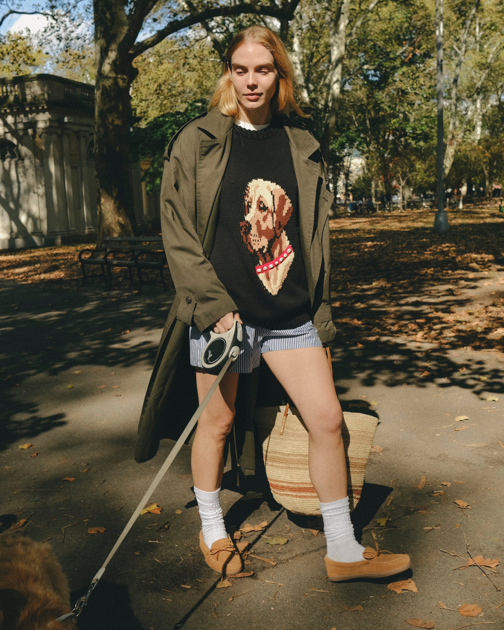 Woman wearing a black knit sweater with an intarsia dog portrait on the front and a red collar detail.