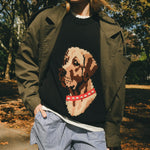 Close-up of woman wearing a black knit sweater with an intarsia dog portrait on the front and a red collar detail.