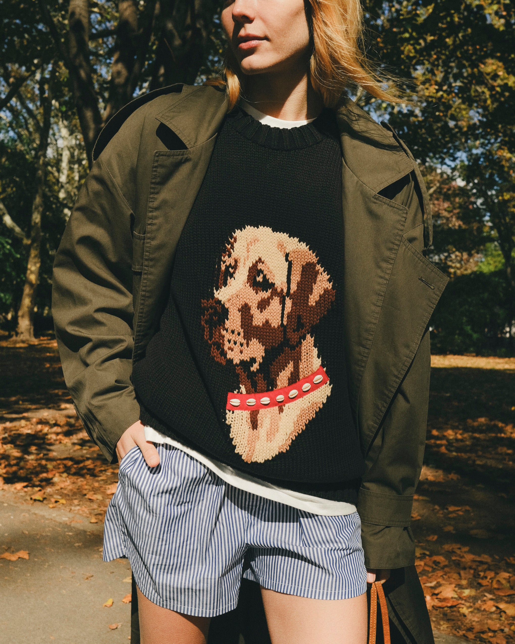 Close-up of woman wearing a black knit sweater with an intarsia dog portrait on the front and a red collar detail.
