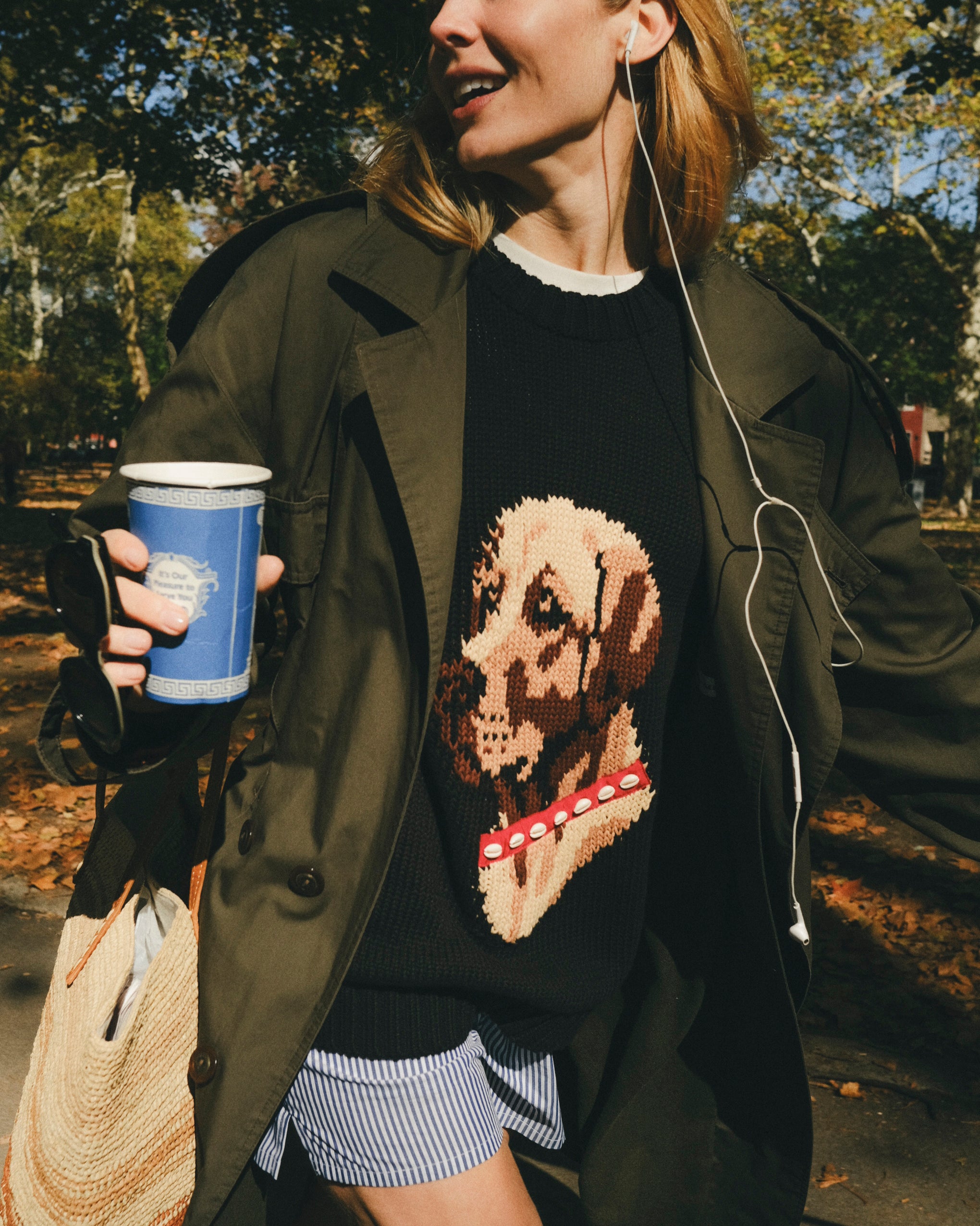 Woman wearing a black knit sweater with ribbed collar, cuffs, and hem, featuring an intarsia dog portrait on the front wearing a red collar with white shell details.