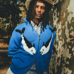 Male model wearing a blue zip-front knit sweater with mirrored fish graphics.