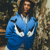Male model wearing a blue zip-front knit sweater with mirrored fish graphics.