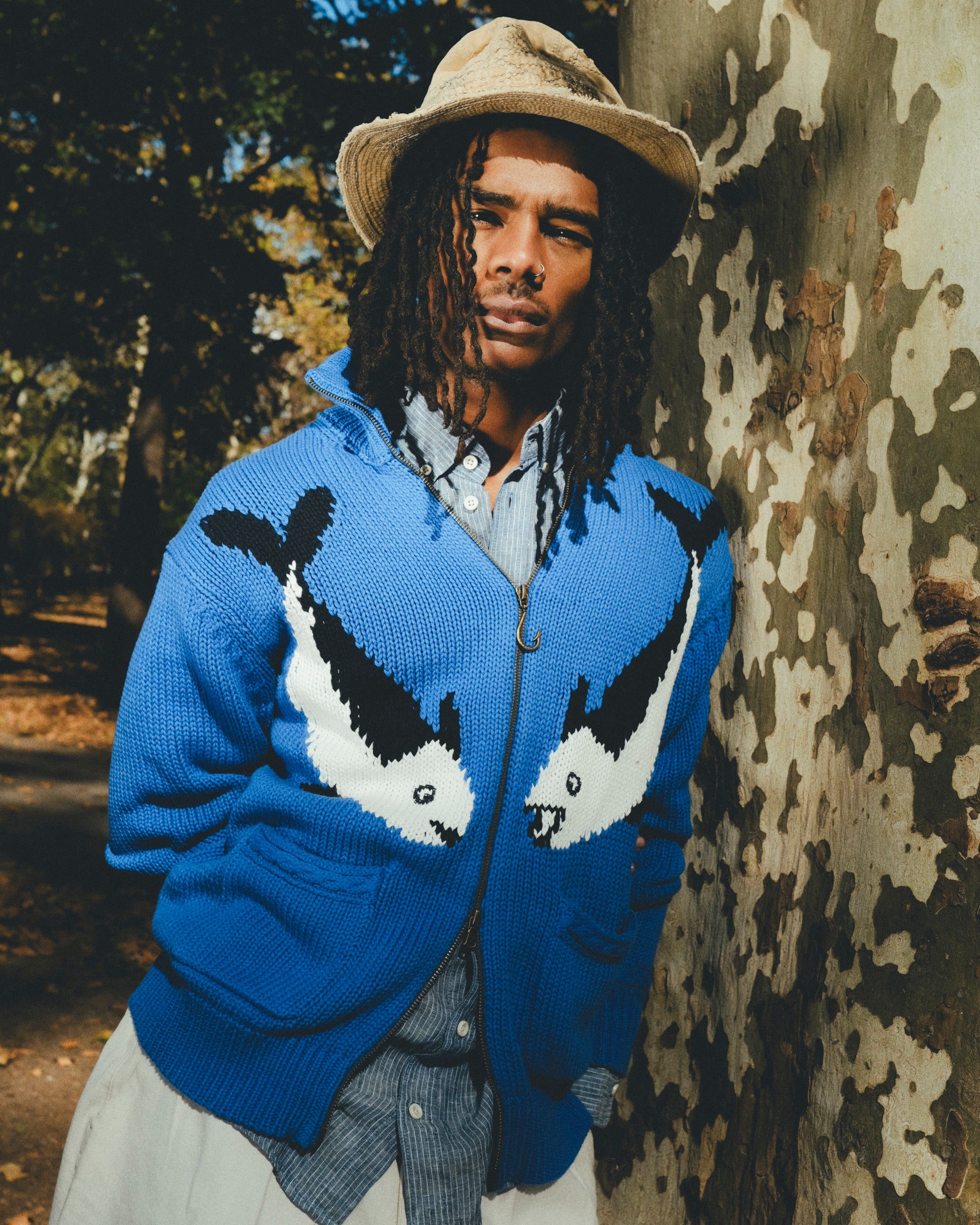 Male model wearing a blue zip-front knit sweater with mirrored fish graphics.