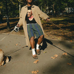 Man wearing a black knit sweater with an intarsia dog portrait on the front and a red collar detail while walking a dog.