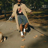 Man wearing a black knit sweater with an intarsia dog portrait on the front and a red collar detail while walking a dog.