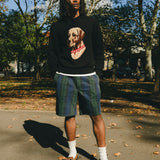 Man wearing a black knit sweater with an intarsia dog portrait on the front and a red collar detail.
