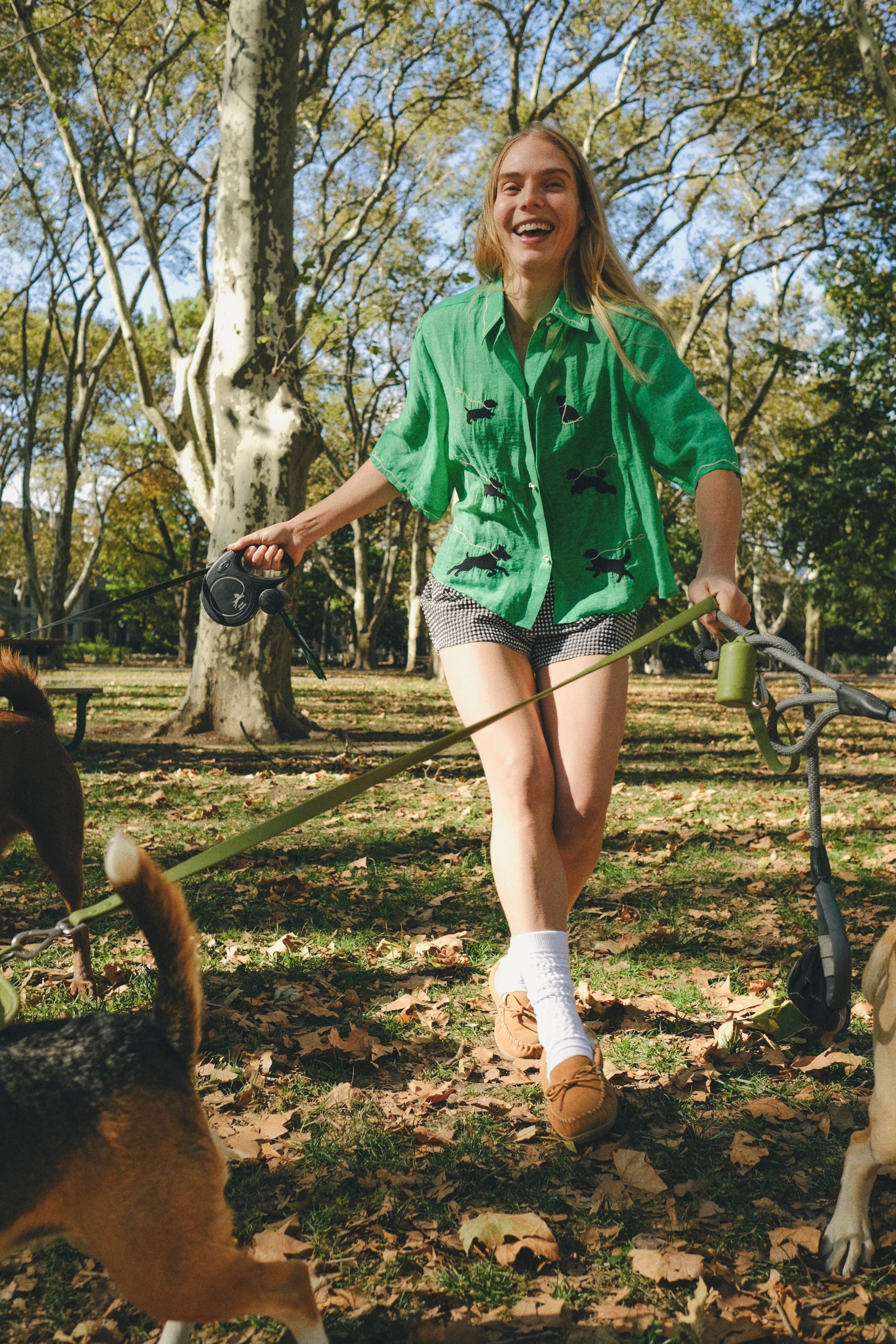 Woman wearing a green cropped cabana shirt with black dog silhouettes and white leash embroidery across the front.