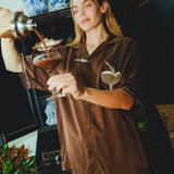 Woman in our espresso martini shirt is pouring her drink into a glass. 