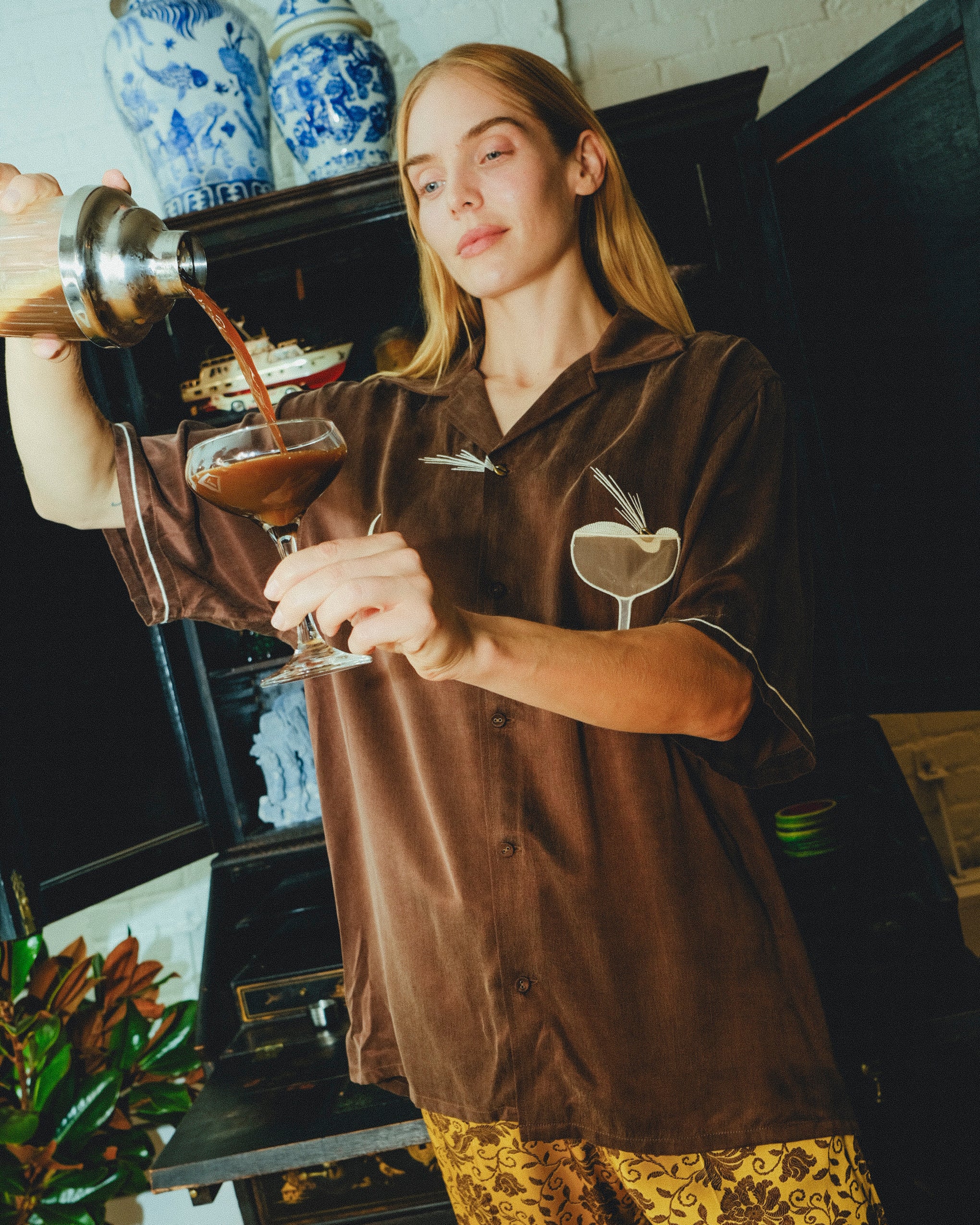 Woman in our espresso martini shirt is pouring her drink into a glass. 