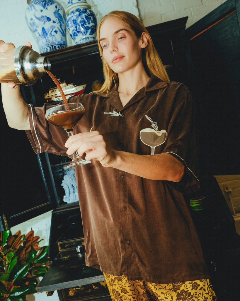 Woman in our espresso martini shirt is pouring her drink into a glass. 
