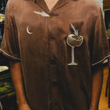 Close-up of man wearing brown espresso martini shirt, with the pocket filled with espresso beans. 