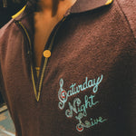 Brown terry cloth polo with 'Saturday Night Live' embroidery on the chest.