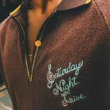 Brown terry cloth polo with 'Saturday Night Live' embroidery on the chest.