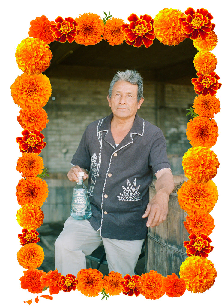 Man poses for camera showing Agua Magica mezcal wearing terrycloth shirt