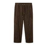 A pair of brown corduroy pants with an elastic waistband and drawstrings, featuring a sewn pleat and zippered side pocket.