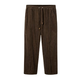 A pair of brown corduroy pants with an elastic waistband and drawstrings, featuring a sewn pleat and zippered side pocket.