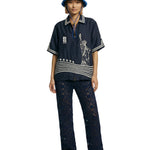 Person wearing a navy blue shirt with a stars and stripes design, black pants, and a blue bucket hat on a white background