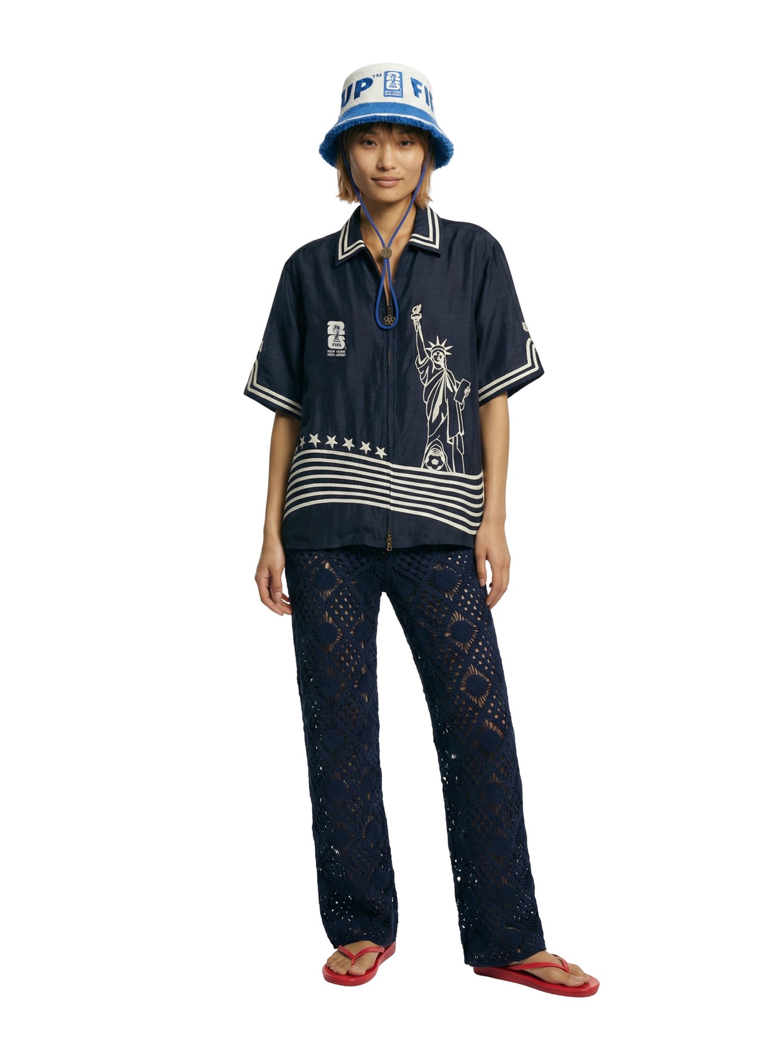 Person wearing a navy blue shirt with a stars and stripes design, black pants, and a blue bucket hat on a white background