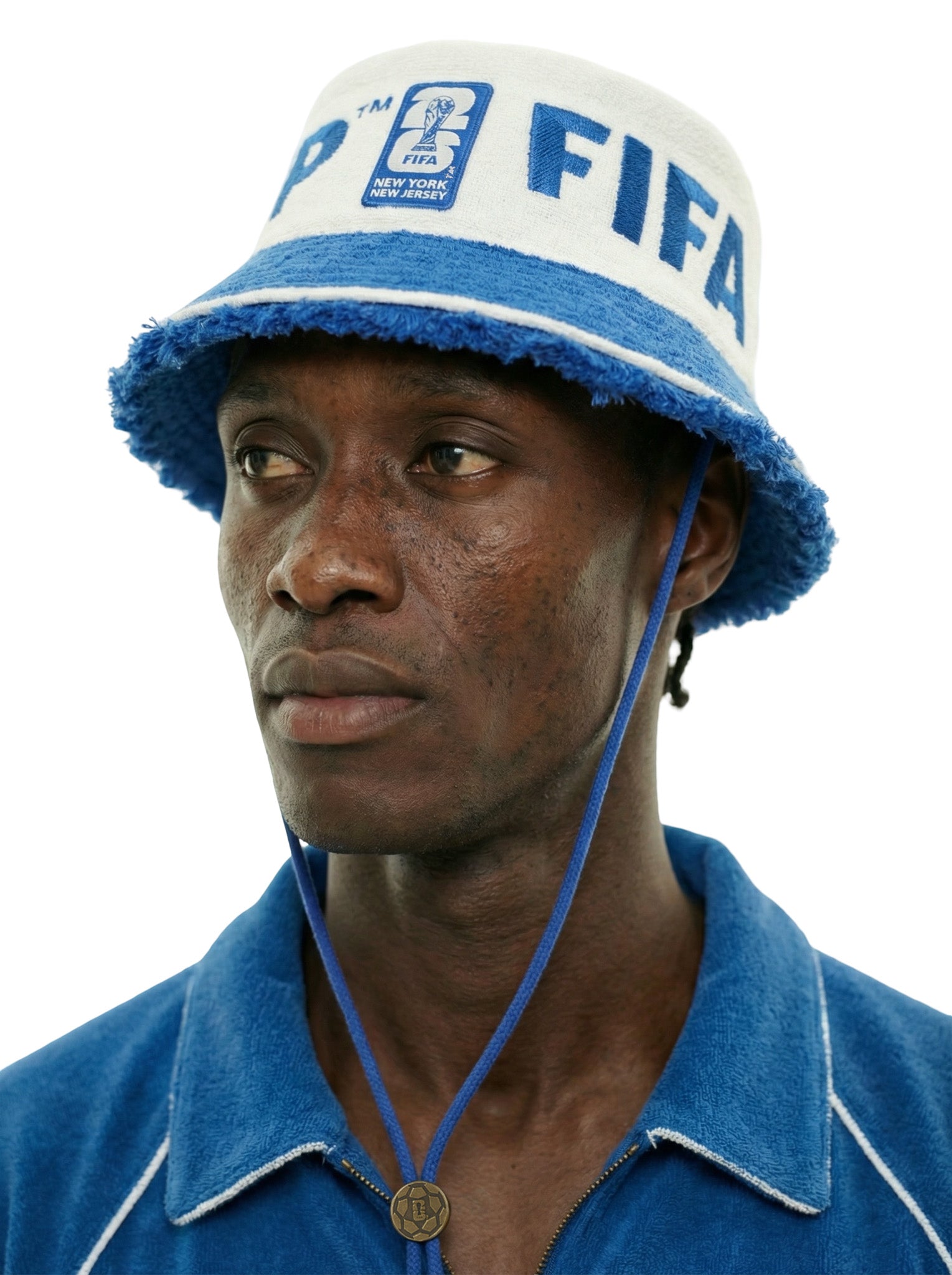 Close-up of model wearing a cream terry bucket hat with blue trim, FIFA lettering, and World Cup 2026 New York New Jersey patch, with chin cord and toggle.